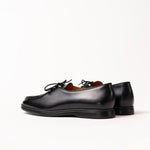 A pair of black leather lace-up shoes with a moc-toe design, shown from a side profile view on a clean white background.