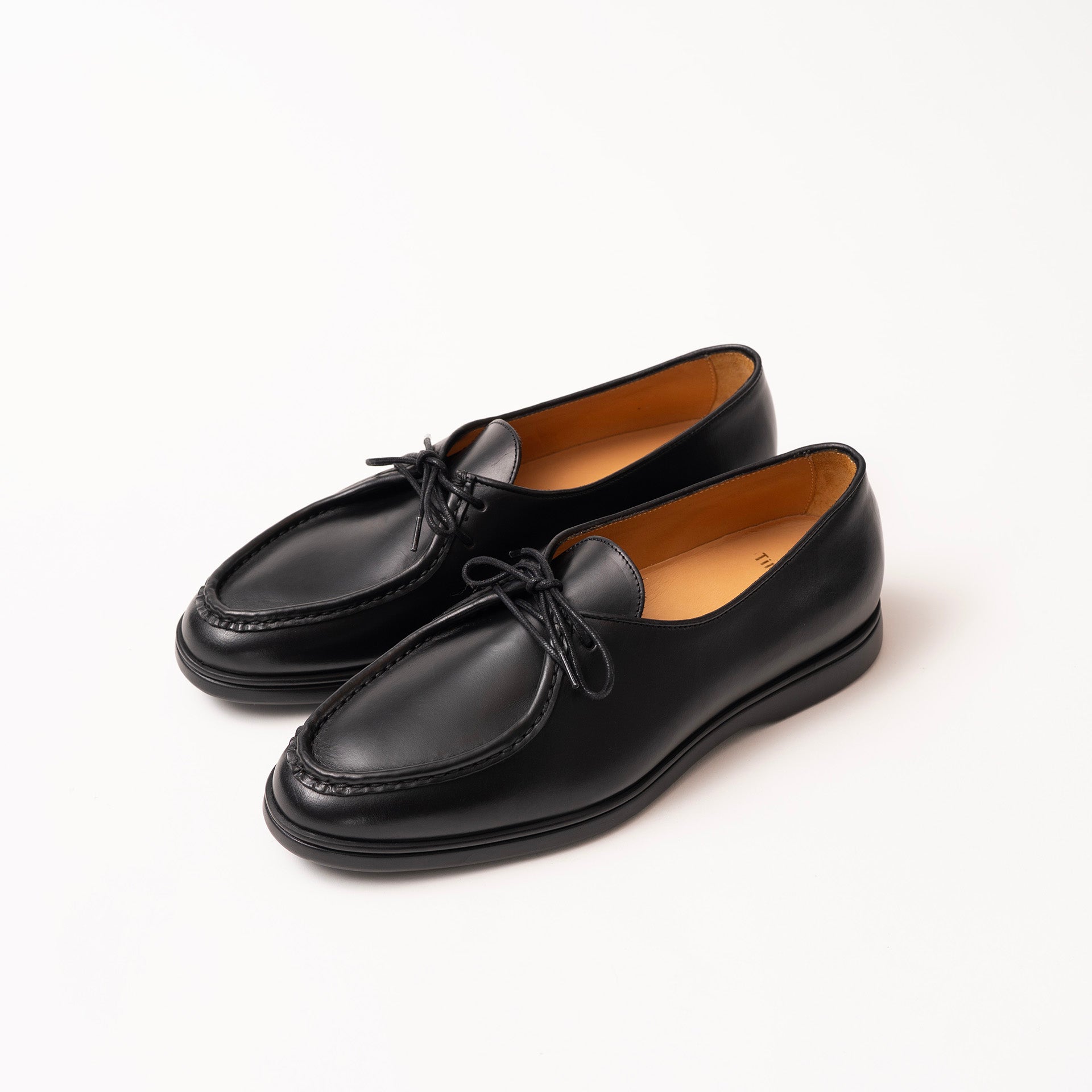 A pair of black leather loafers with black laces by Timothée Paris, displayed on a clean white background.
