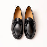 A pair of black leather loafers with moc toe and matching black laces by Timothée Paris, photographed from a top-down angle on a clean white background.