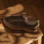 Brown suede and leather shoe Yport by Timothée Paris on a wooden stool with a warm, wooden background