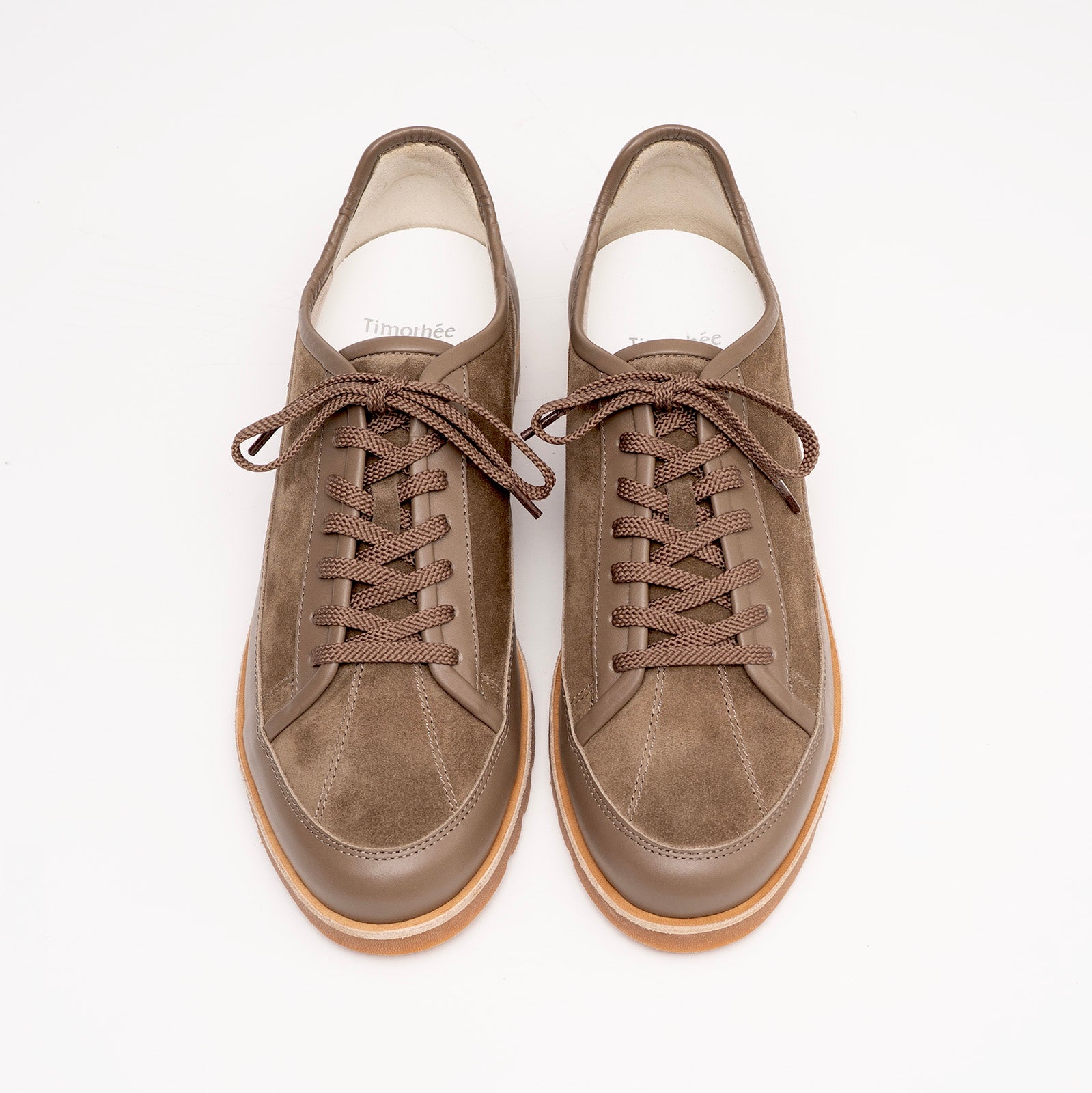 Pair of brown suede and leather sneakers with latex sole by Timothée Paris on a light gray background