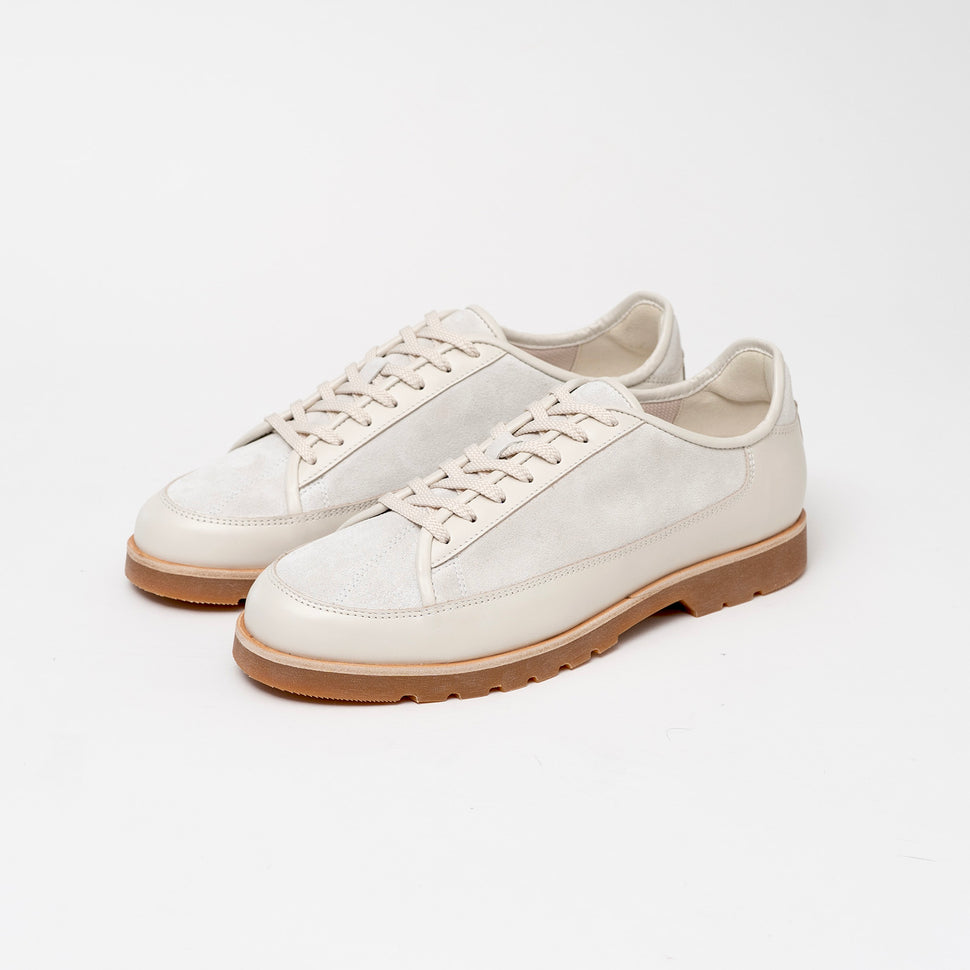 Pair of Timothee Paris white sneakers with brown soles on a light gray background