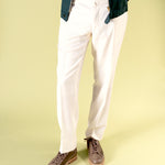 Person wearing white pants and brown leather and suede shoes  with latex sole by Timothée Paris on a light green background
