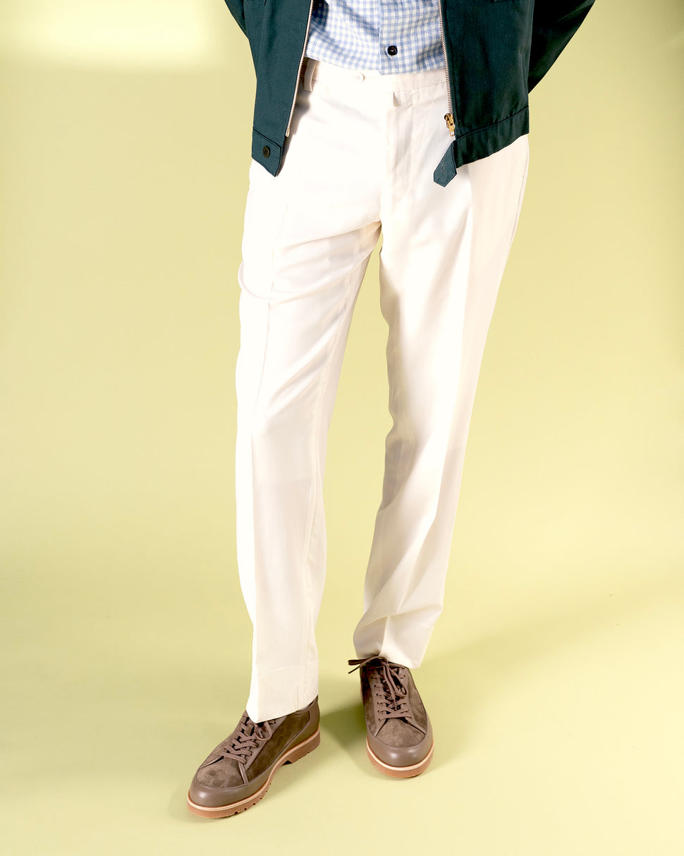 Person wearing white pants and brown leather and suede shoes  with latex sole by Timothée Paris on a light green background