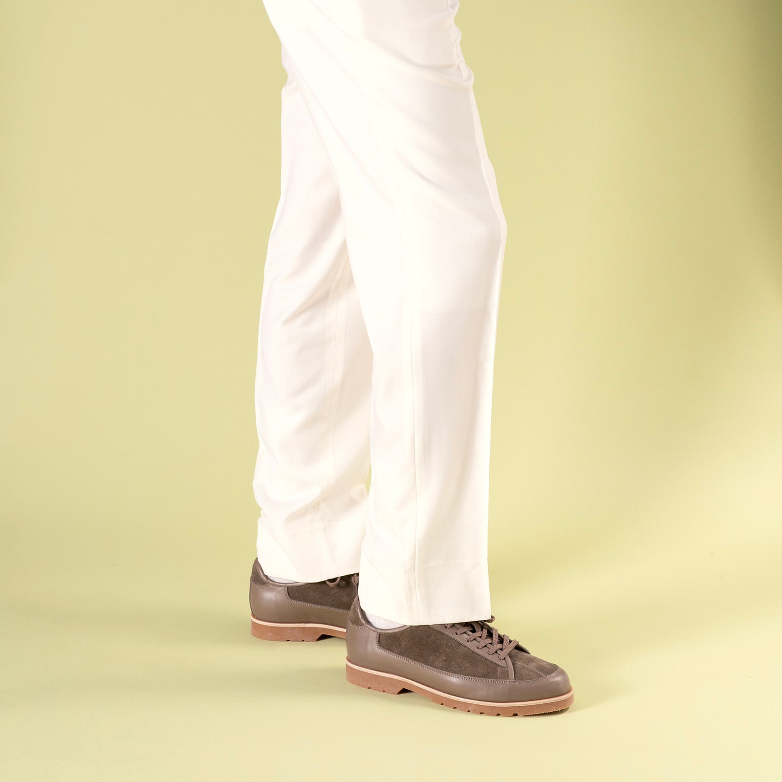 Timotée Paris Brown shoes Yport worn with white pants on a light green background

