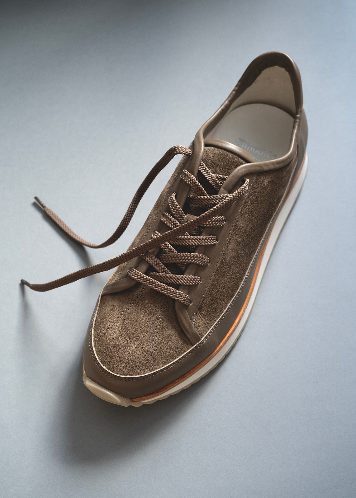 Still life of the Timothée Paris Louviers sneaker in brown leather, handcrafted with minimalist design