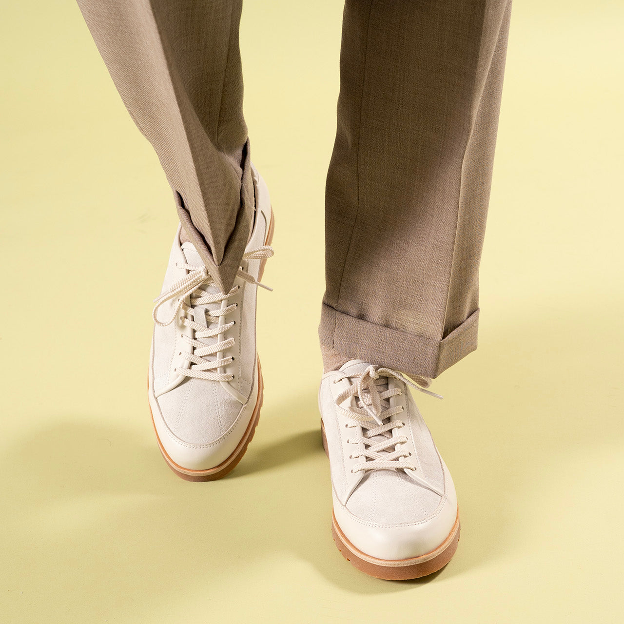 Timothee Paris White shoes with brown soles worn with beige pants on a light yellow background