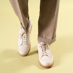Timothee Paris White shoes with brown soles worn with beige pants on a light yellow background