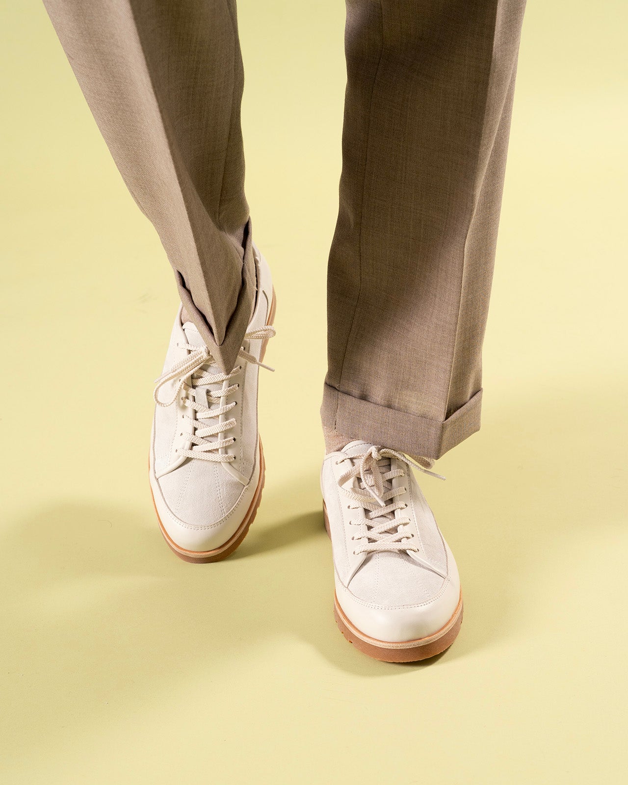 Timothee Paris White shoes with brown soles worn with beige pants on a light yellow background